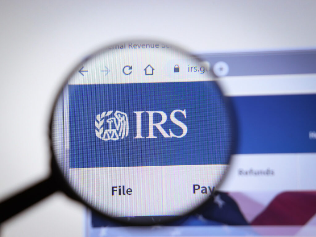 Magnifier focuses on IRS logo on IRS website hopepage. Editorial credit: Postmodern Studio / Shutterstock.com