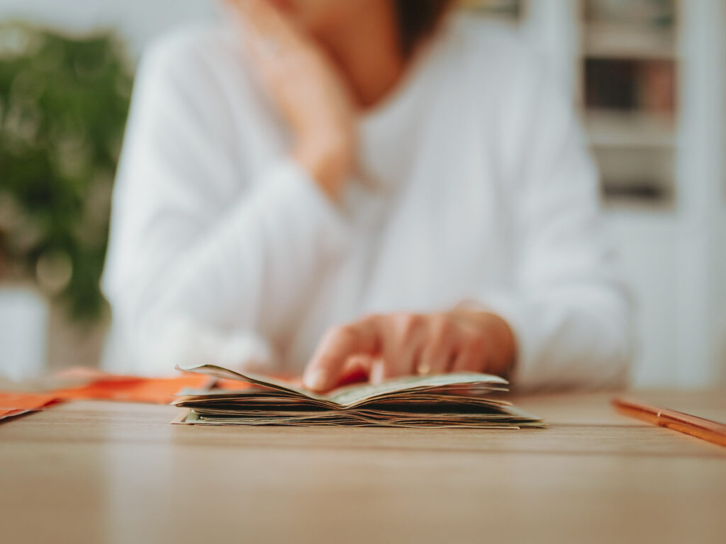 A woman sits at a table studying a small notebook