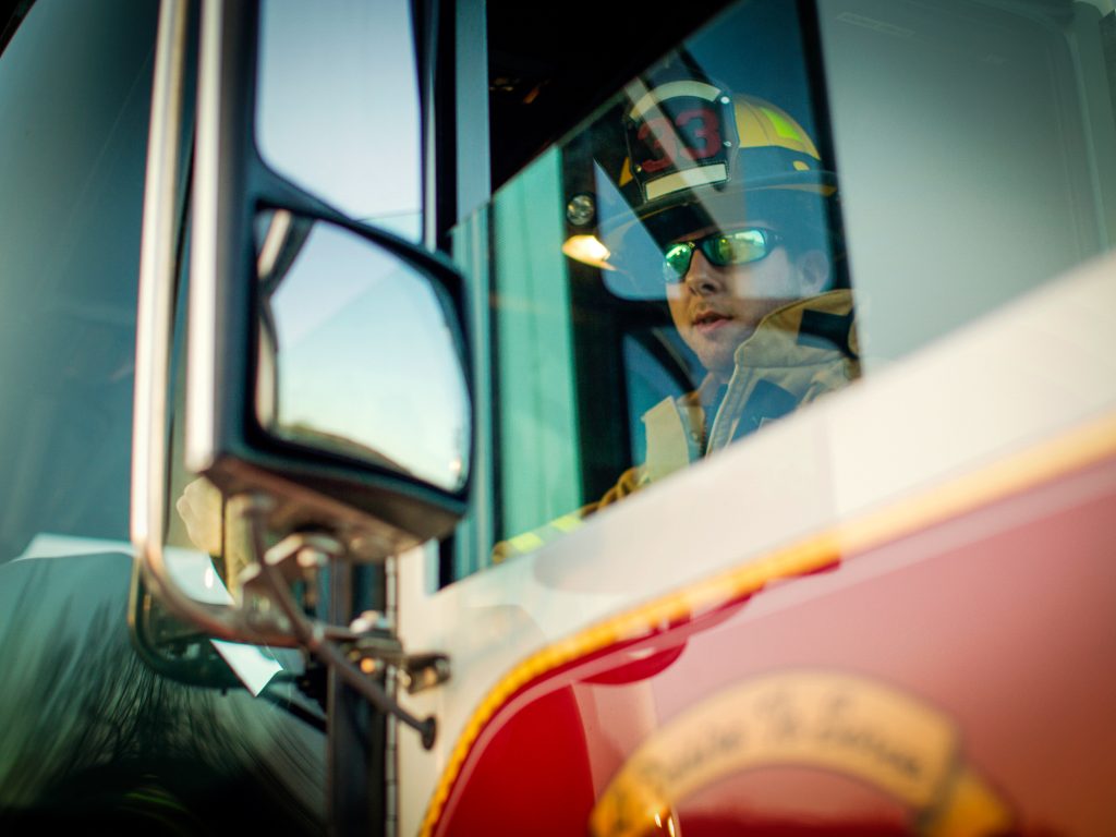 A firefighter looks through the window of a fire engine