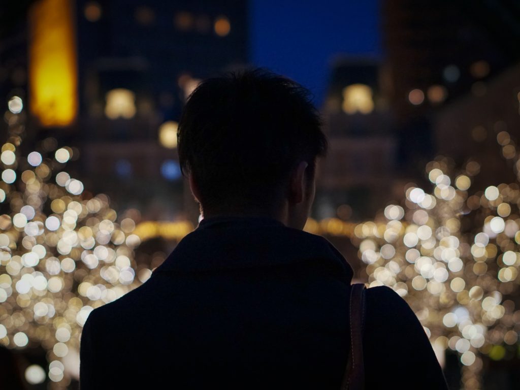 Silhouette of Asian man back, alone in Christmas illumination light in winter park
