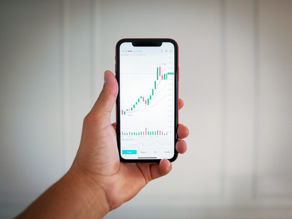 a person holding a smartphone displaying a stock chart