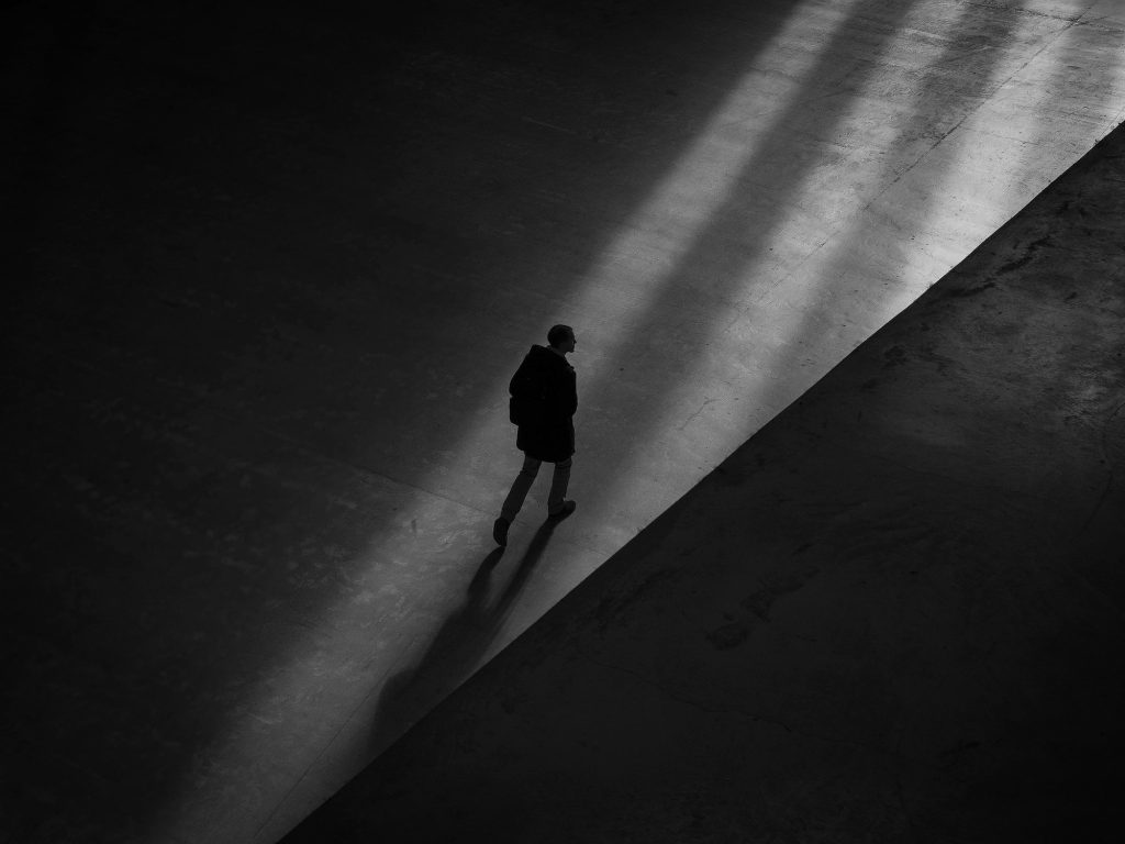 man walks through shadows on an empty street