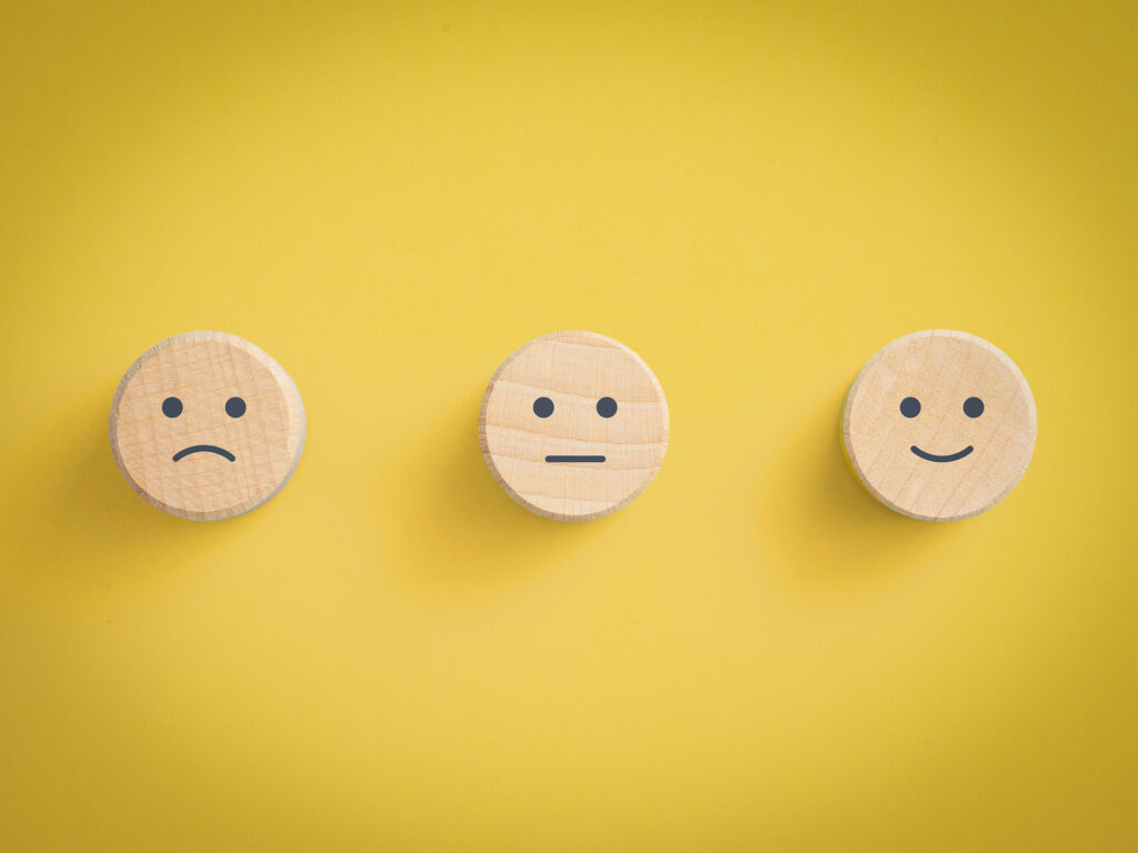 unhappy, neutral and happy icons against a yellow background